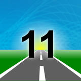 The number “11” in bold black text stands on a road leading toward a glowing horizon, set against a blue sky and green landscape.