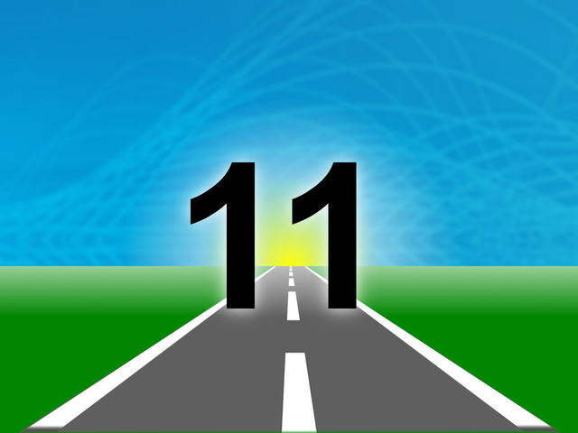The number “11” in bold black text stands on an open road stretching toward a glowing horizon with blue sky and green fields.