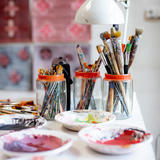 A table with brushes, colors, a lamp and creative background.